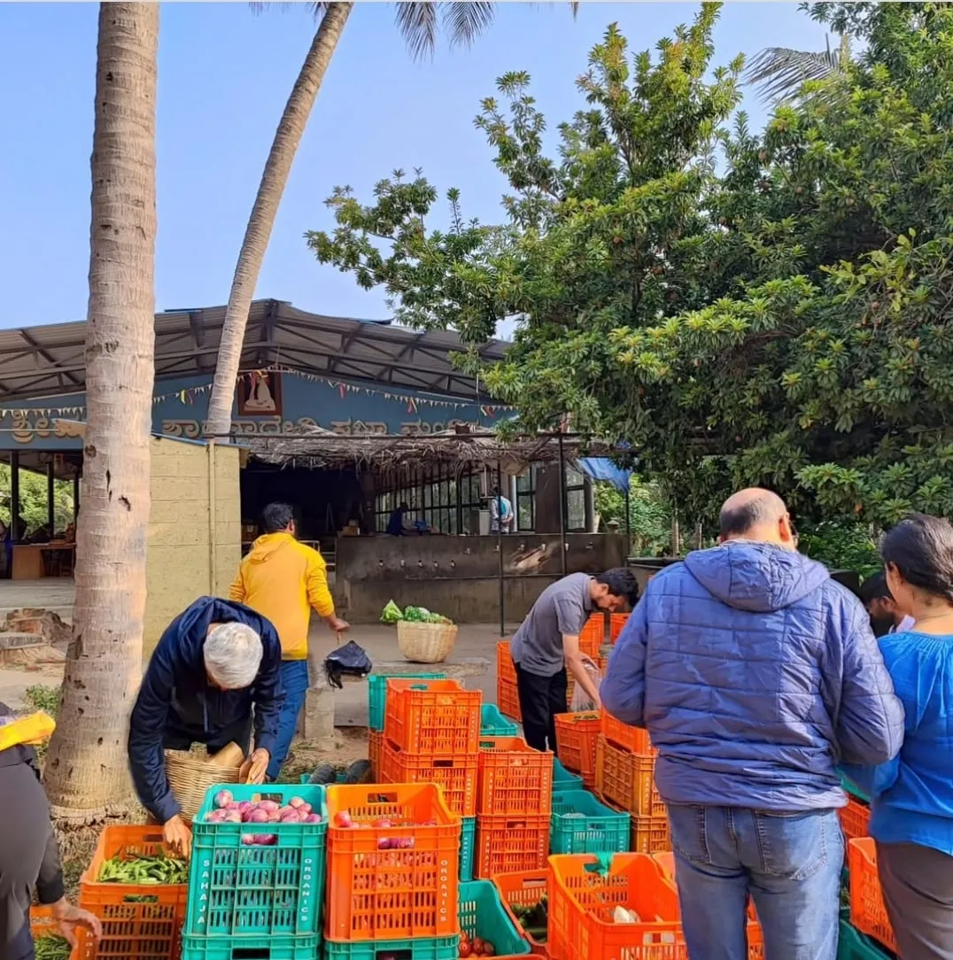 Farmers and visitors around crates of fresh produce at the Ragi Kana santhe