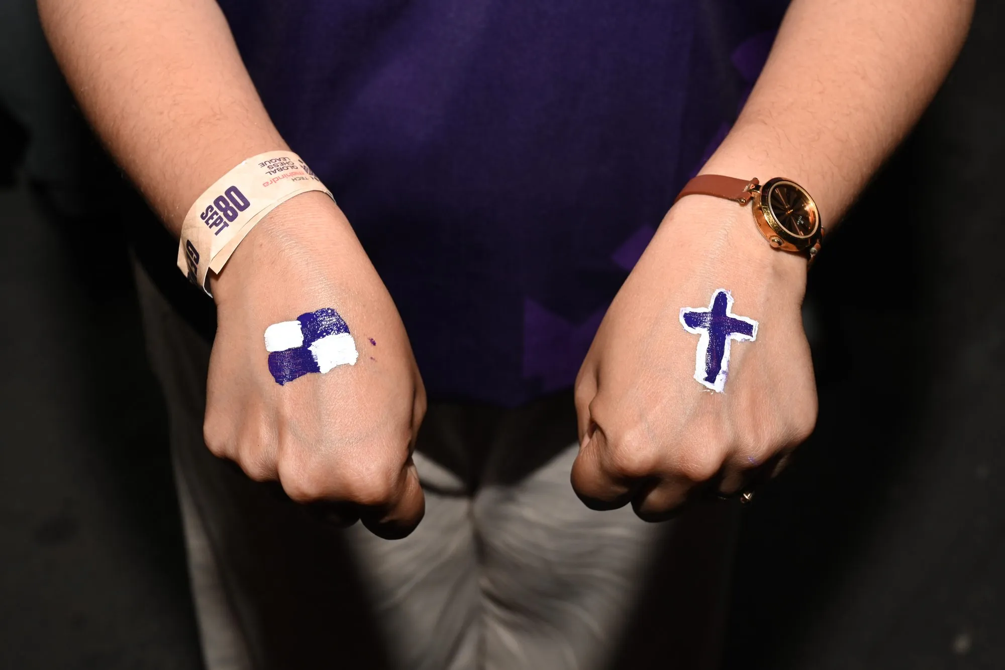 Close-up of two fists painted with a chessboard square and a chess cross