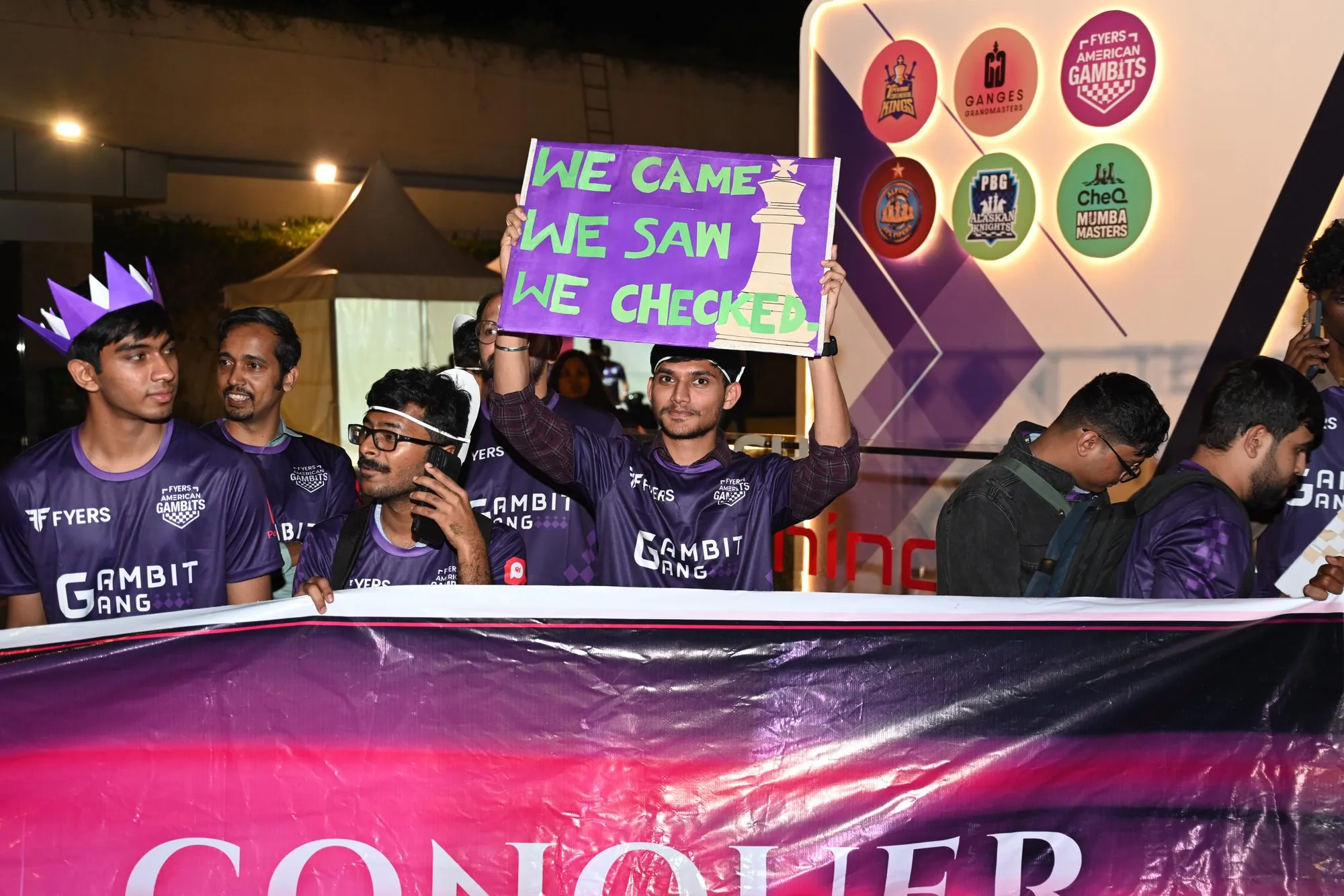 Volunteers raising a We came, we saw, we checked sign behind the team banner