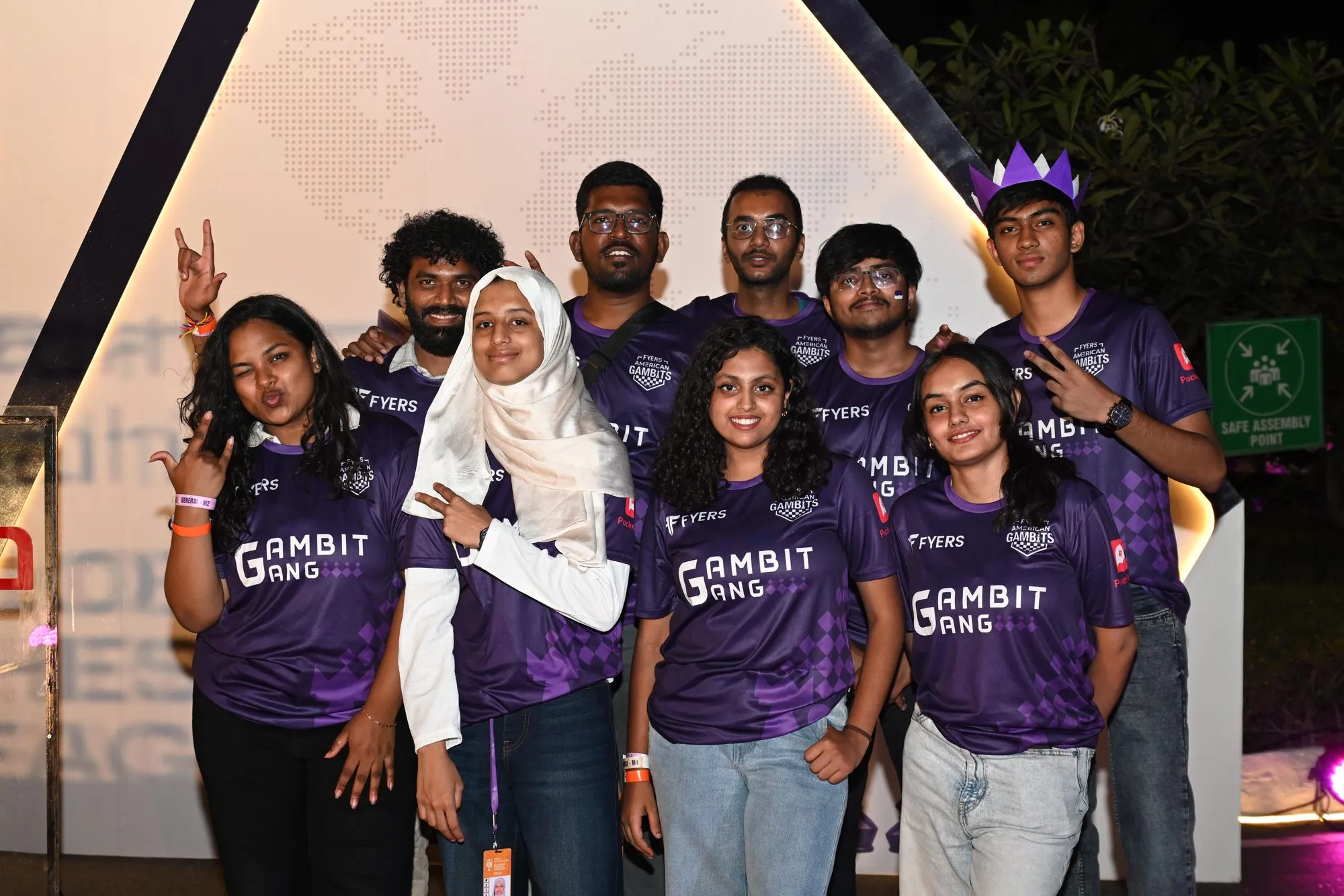 A group of ten Gambits Gang volunteers posing at night in jerseys and crowns