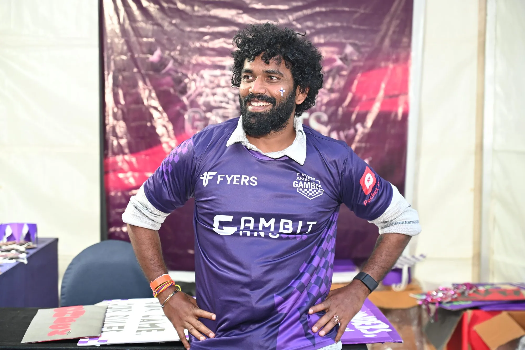 A laughing volunteer in a Gambit Gang jersey, hands on hips, in the fan tent